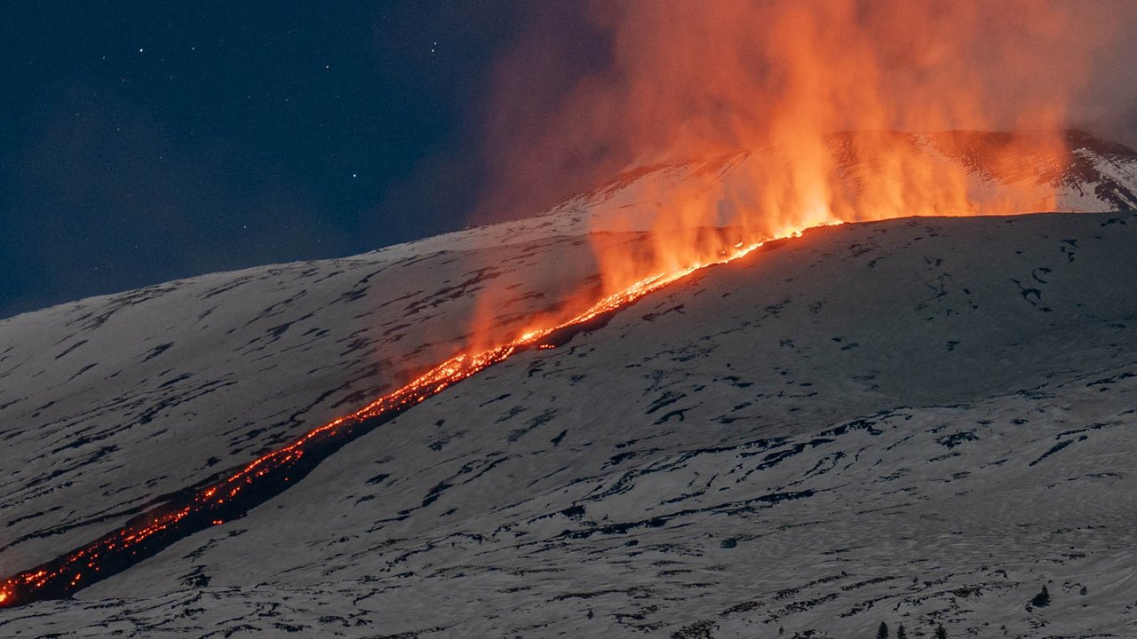 Seorang pria berjalan di depan Gunung Etna yang erupsi di Sisilia, italia, 1(12/02/2025).