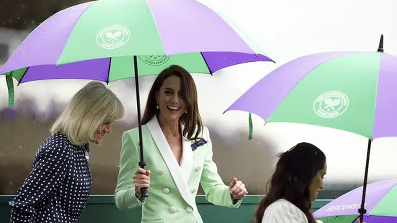 Blazernya serasi dengan warna hijau dari payung Wimbledon yang harus dipegangnya sebentar saat ia, seperti penggemar lainnya, berlindung dari hujan musim semi di London. (Zac Goodwin/Pool Pho)