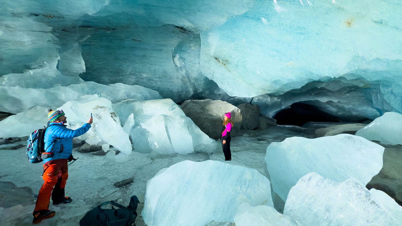 Pendaki berjalan dalam gua es yang terbentuk oleh air saat musim panas pada gletser Morteratsch yang  mencair akibat perubahan iklim di Pegunungan Alpen, Swiss, Sabtu (21/02/ 2025) waktu setempat.