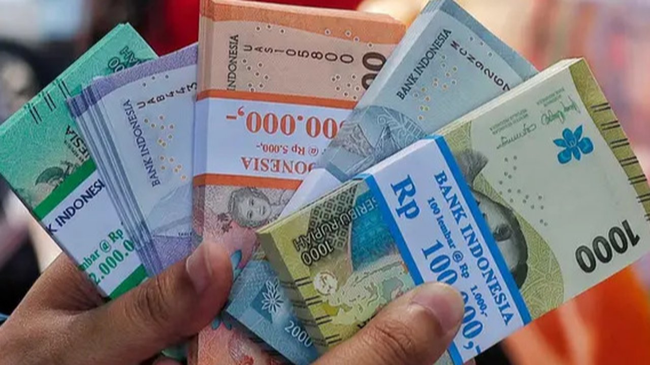 Seorang pria menunjukkan uang kertas Rupiah yang baru, yang akan diberikan kepada anggota keluarganya saat perayaan Idul Fitri, di Jakarta pada 28 Maret 2024. (Adek BERRY/AFP)