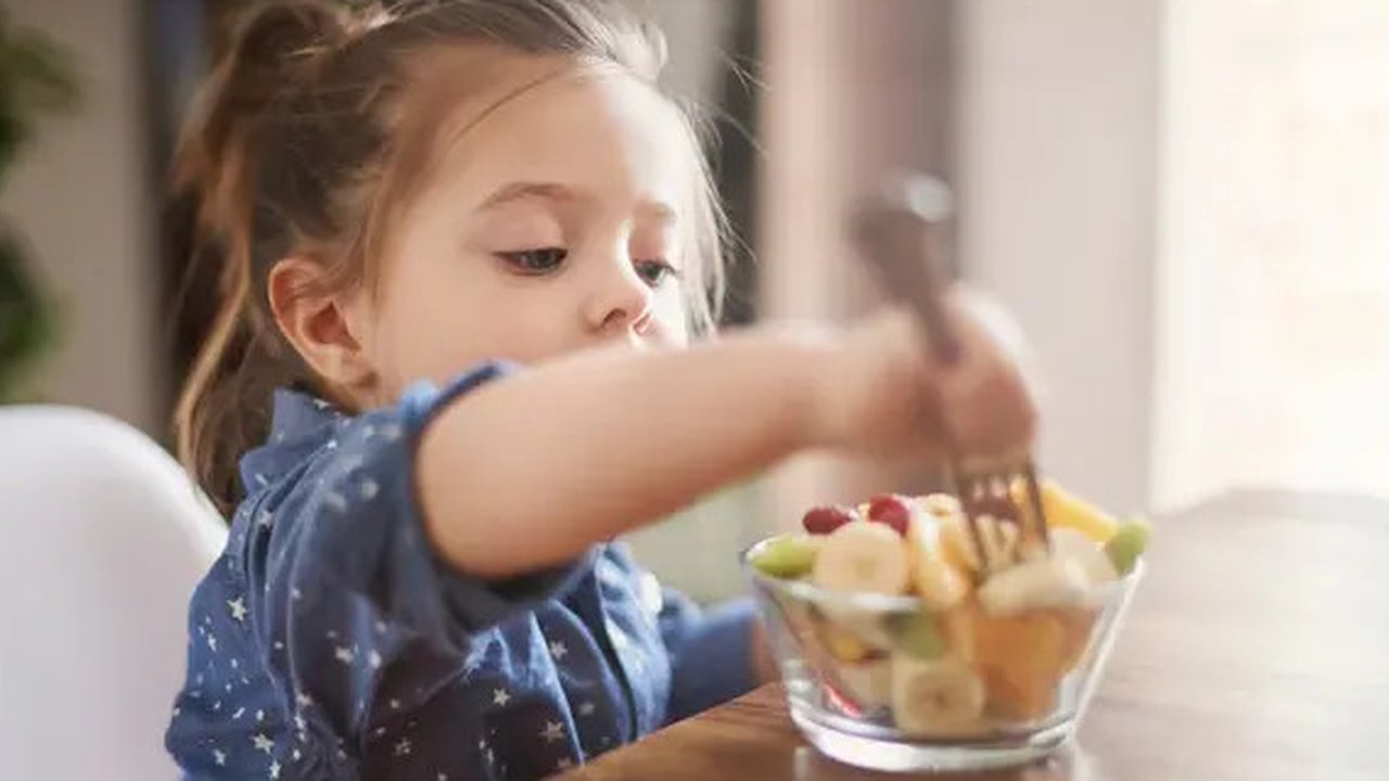 Anak perempuan yang ingin memakan buah-buahan yang sudah dipotongi orangtuanya (Foto dok : Freepik/gpointstudio).