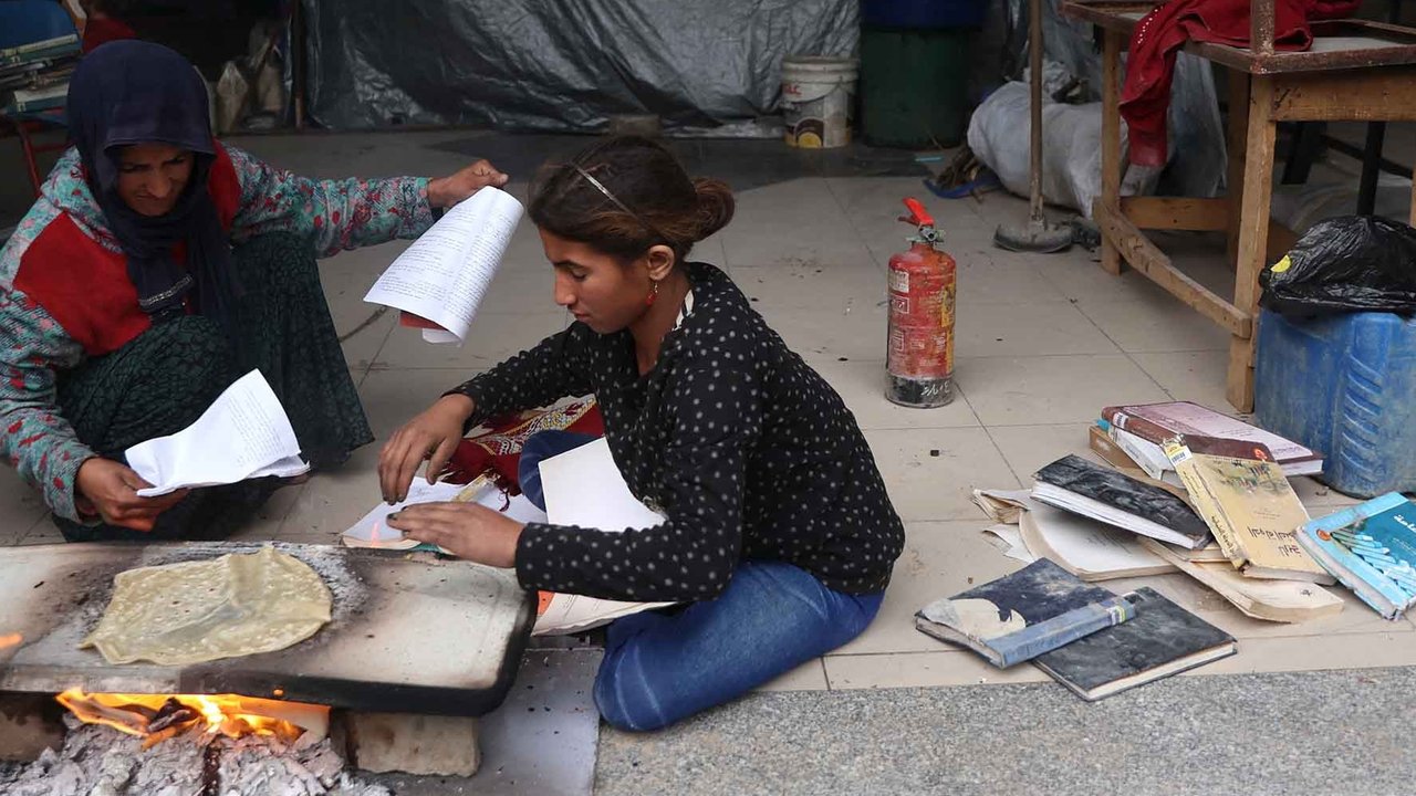 Warga yang mengungsi membakar kertas buku yang dikumpulkan dari Universitas Islam yang hancur untuk memasak makanan di Kota Gaza Palestina, (21/03/2025) waktu setempat.