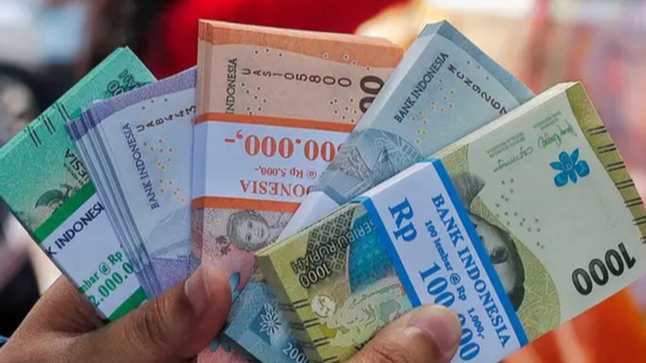 Seorang pria menunjukkan uang kertas Rupiah yang baru, yang akan diberikan kepada anggota keluarganya saat perayaan Idul Fitri, di Jakarta pada 28 Maret 2024. (Adek BERRY/AFP)