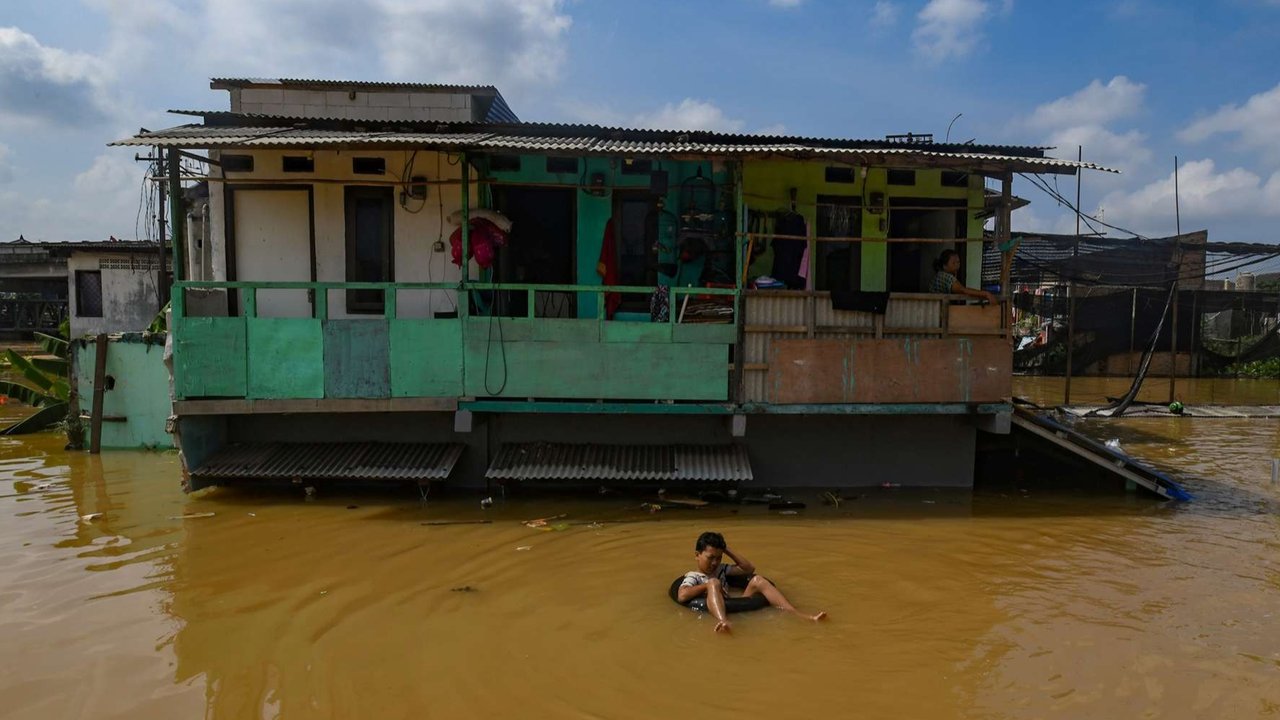 Seorang anak bersantai di atas ban bekas saat banjir merendam permukiman di sekitar Sungai Ciliwung, Jakarta Timur, Senin (3/3/2025). Banjir akibat luapan Sungai Ciliwung merendam sejumlah wilayah di Jakarta dengan ketinggian mencapai 2 meter.