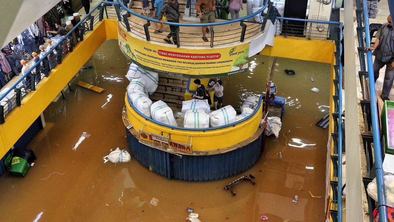 Seorang pekerja membawa barang-barang melewati banjir yang merendam Pasar Cipulir, Jakarta, Selasa (4/3/2025).