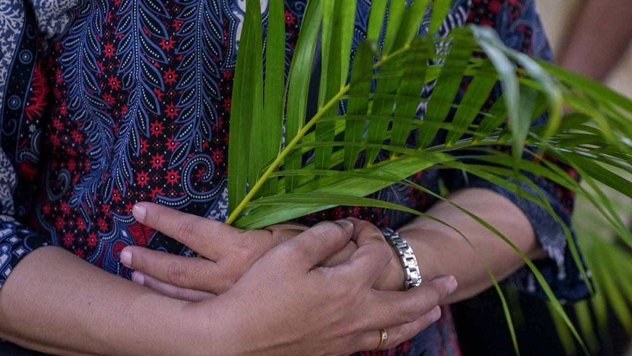 Umat Katolik memegang daun palem saat mengikuti prosesi Minggu Palma di Gereja Kelahiran Bunda Maria di Surabaya, Minggu (13/04/2025).