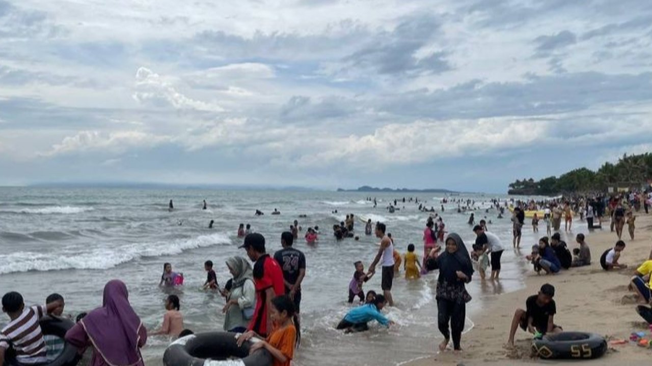 Ribuan wisatawan memadati Pantai Anyer, Banten, pada H+2 Lebaran untuk menikmati liburan, meskipun cuaca mendung dan gerimis.