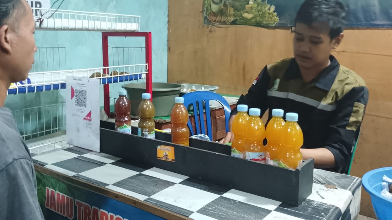 Pemilik usaha Jamu Tradisional Herbal Kaliwungu, Gema Nur Hidayat saat melayani pembeli di warungnya.