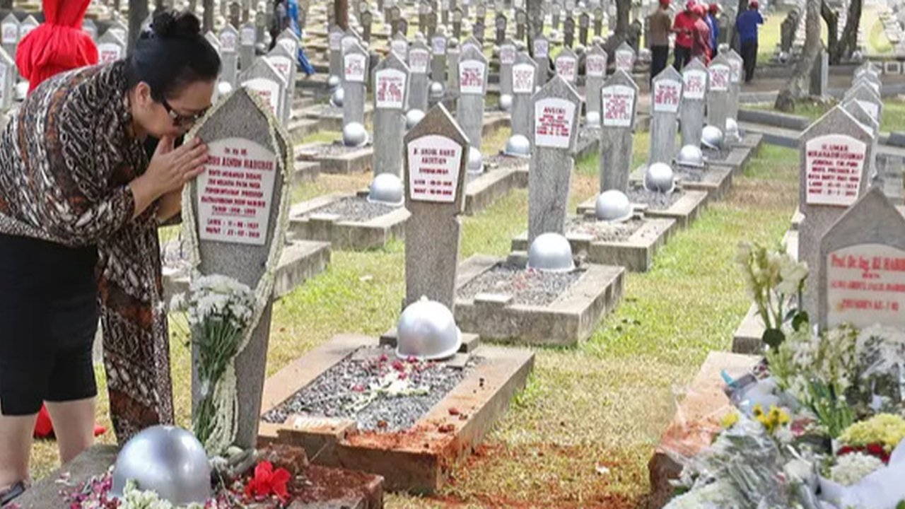 Warga mencium batu nisan di makam Hasri Ainun Besari yang bersebelah dengan makam sang suami,  Presiden ke-3 RI BJ Habibie di TMP Kalibata, Jakarta, Jumat (13/9/2019). Sesuai permintaannya se
