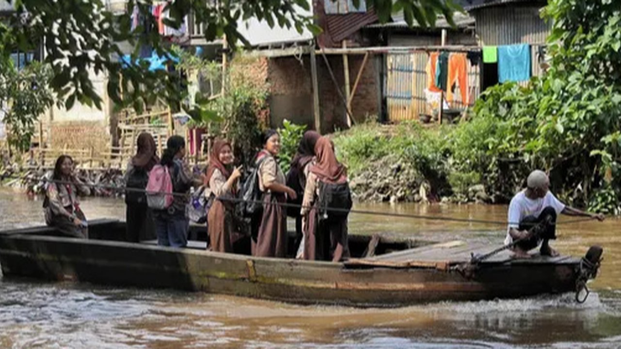 Dua orang pelajar bersiap naik perahu eretan untuk menyeberangi kali Ciliwung di kawasan Manggarai, Jakarta, Rabu (14/5/2025). (Liputan6.com/Angga Yuniar)