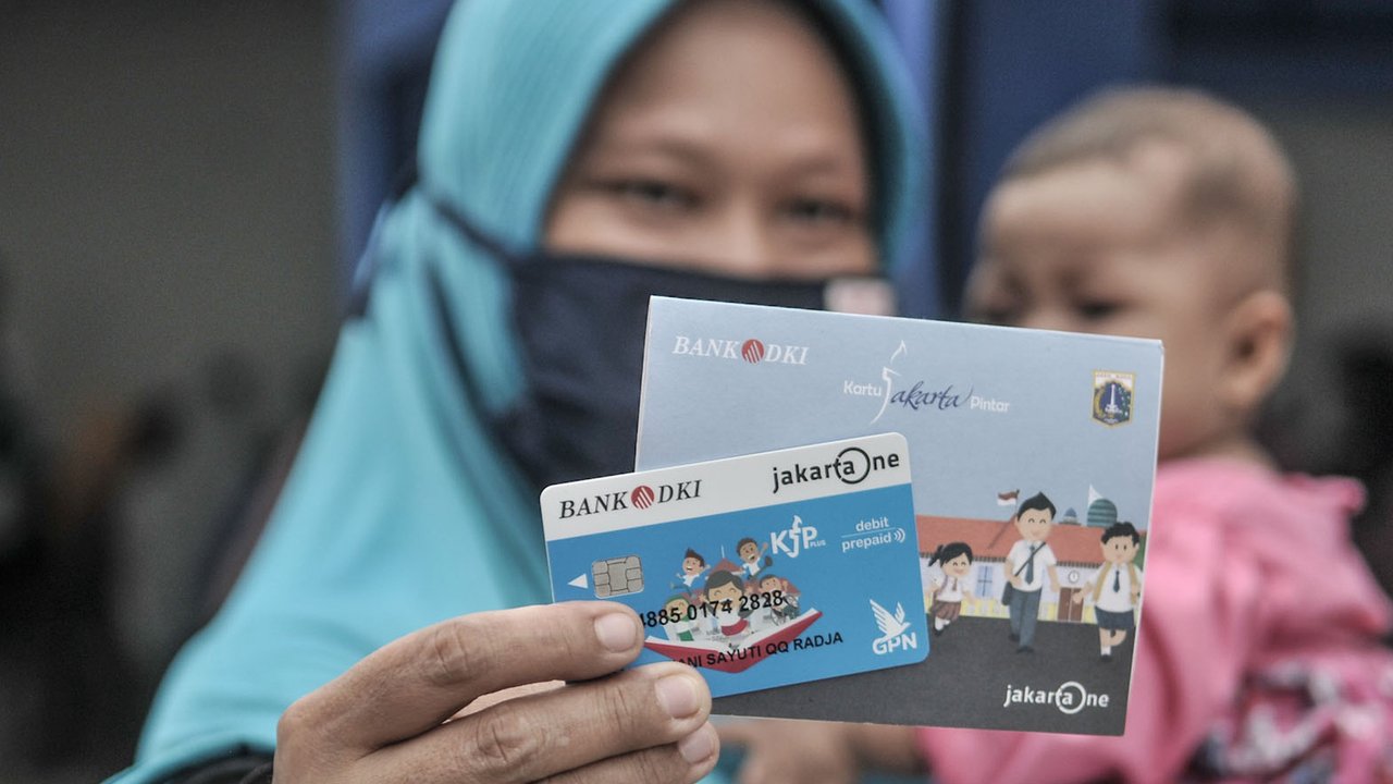 Orangtua dari anak penerima saat menunjukkan KJP yang baru diterima di kawasan Matraman, Jakarta, Selasa (24/11/2020). Penyaluran KJP plus tahap kedua ini menggunakan data baru berdasarkan pembaruan berkas warga penerima yang rampung pada bulan Oktober lalu. (merdeka.com/Iqbal S. Nugroho)