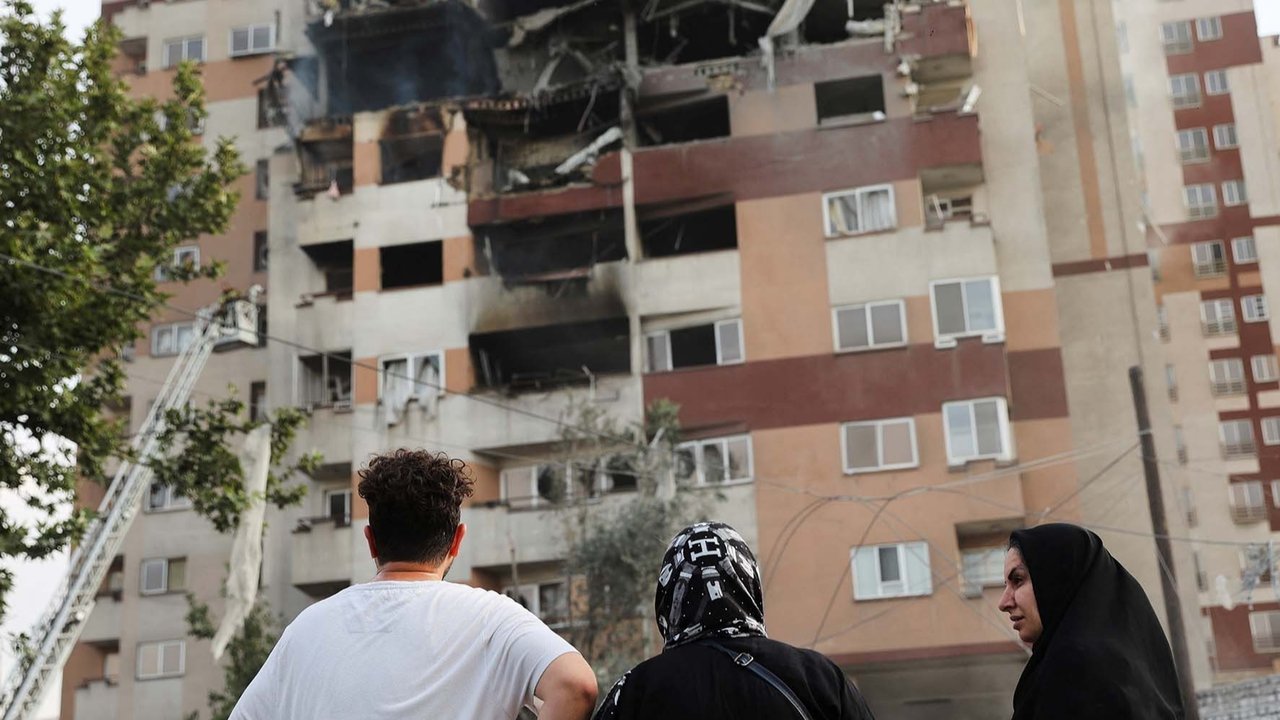 Warga  berkumpul di dekat bangunan yang rusak akibat serangan Israel, di Teheran, Iran, Jumat (13/06/2025).