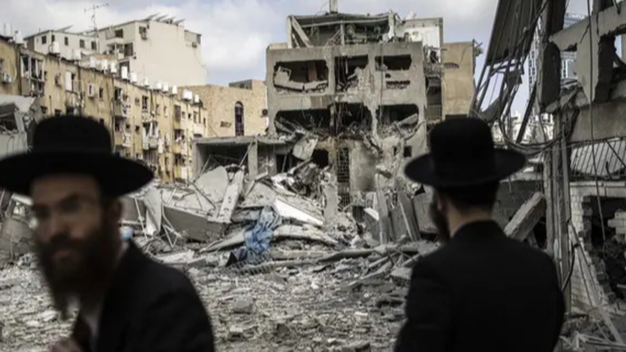 Warga mengamati apartemen yang rusak di Teheran, Iran, akibat serangan udara Israel pada Jumat (13/6/2025). (Dok. AP/Vahid Salemi)