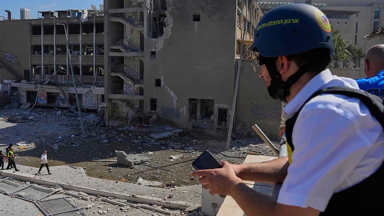 Tim tanggap darurat Israel memperingatkan warga di lokasi serangan rudal Iran di Haifa, Israel, Jumat (20/06/2025). AP/Baz Ratner
