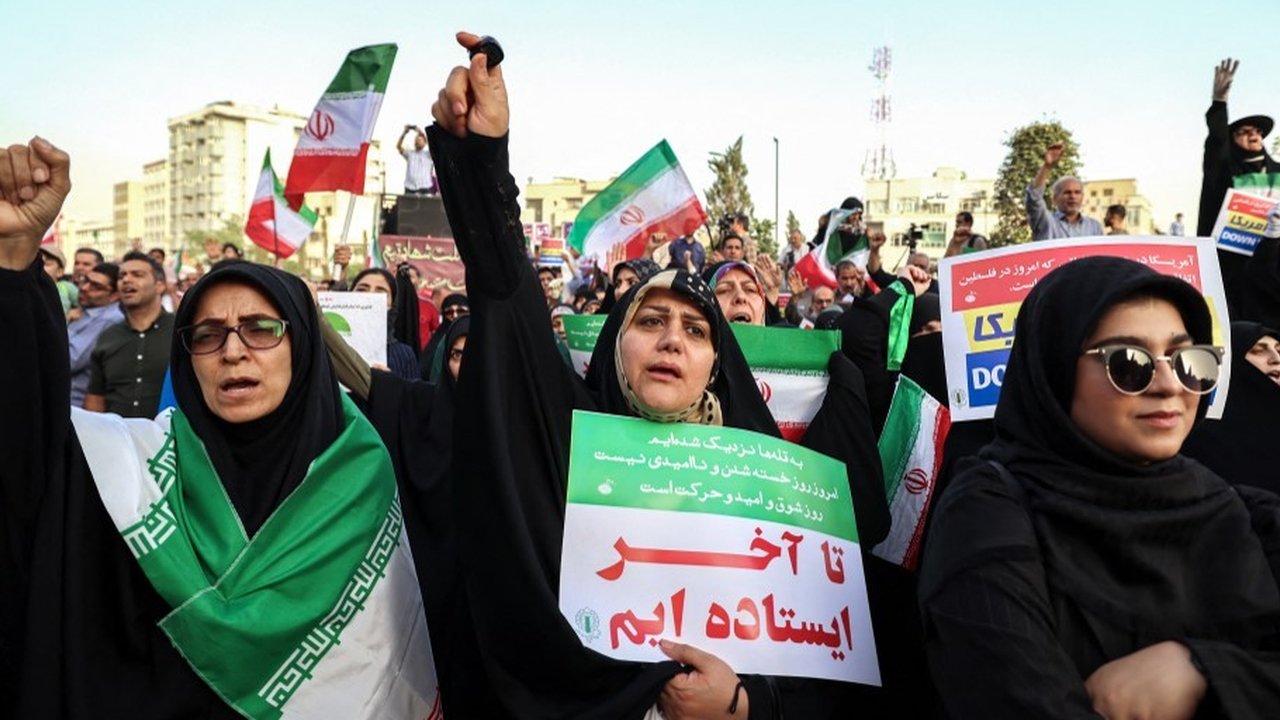 Warga Iran meneriakkan slogan dan mengibarkan bendera saat merayakan gencatan senjata antara Iran dan Israel di Lapangan Enghelab, Teheran, pada Selasa (24/6/2025).