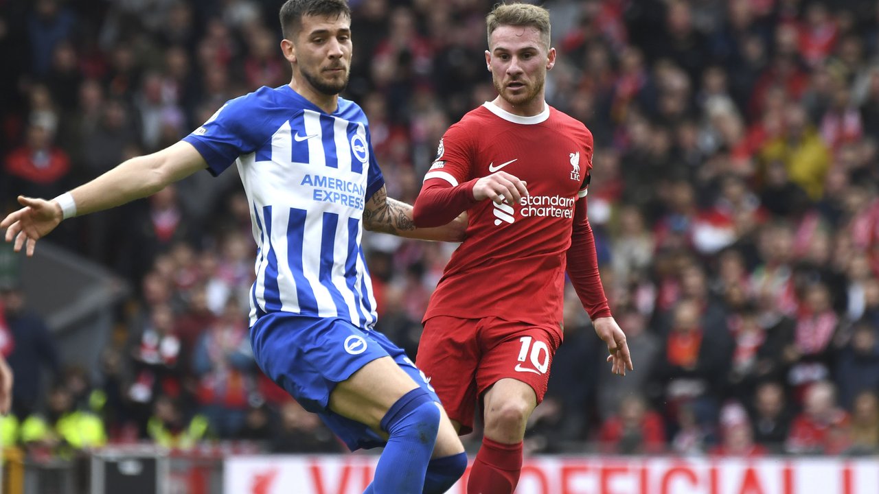 Gelandang Liverpool, Alexis Mac Allister (kanan) melepaskan umpan di depan gelandang Brighton and Hove Albion, Jakub Moder pada laga pekan ke-30 Premier League 2023/2024 di Anfield Stadium, Liverpool, Minggu (31/3/2024). (AP Photo/Rui Viera)