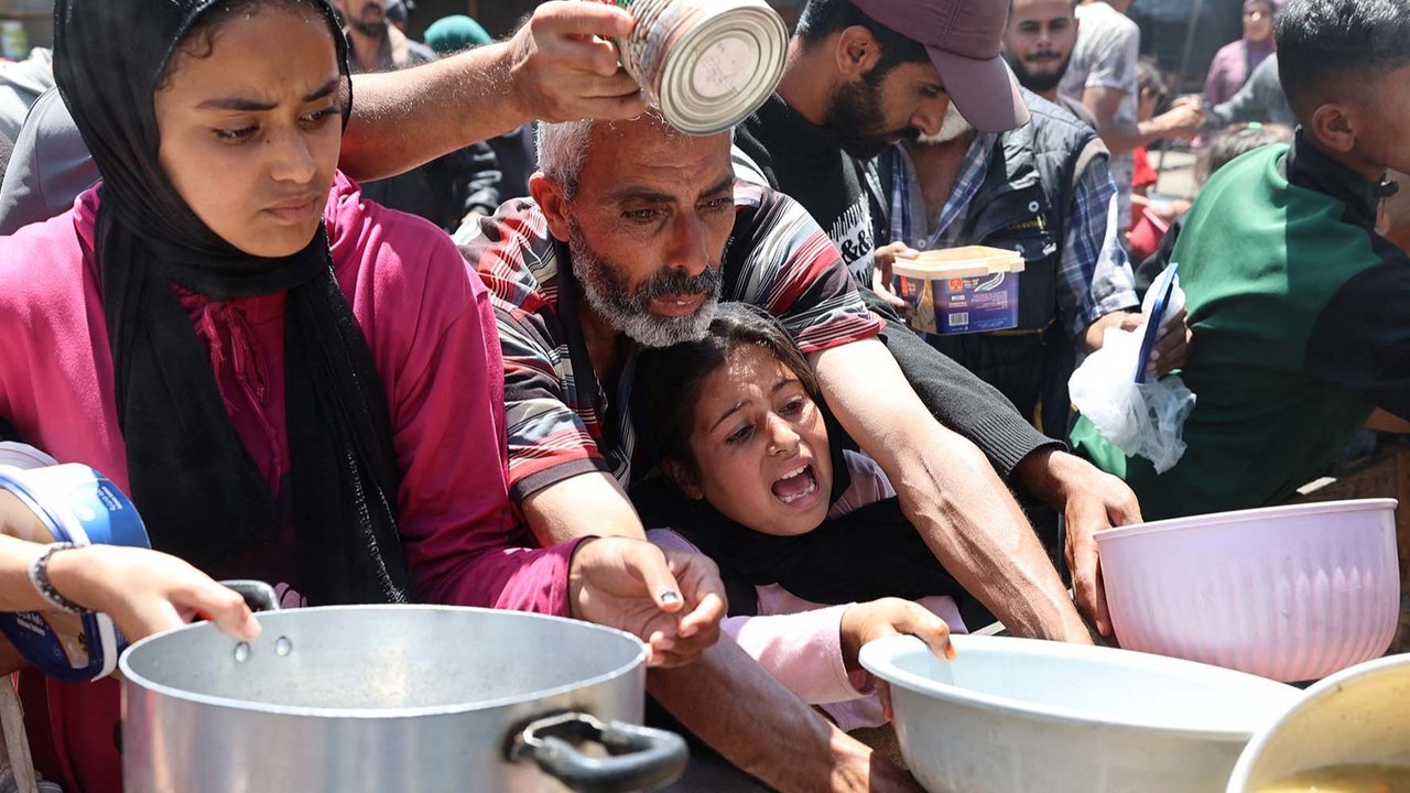 Warga Palestina mengantri untuk mendapatkan makanan hangat di dapur amal di kamp pengungsi Nuseirat di Jalur Gaza bagian tengah, Minggu (04/05/ 2025).