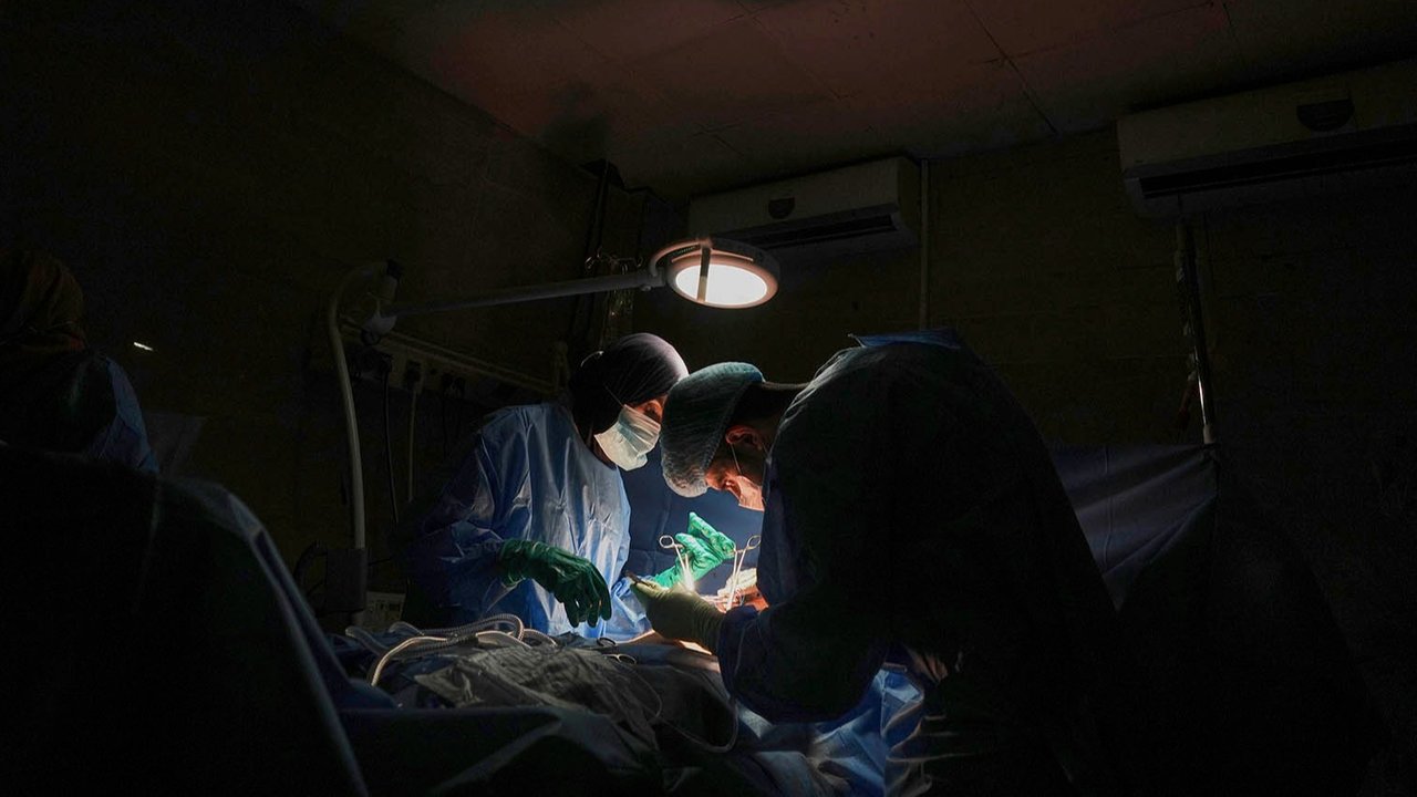 Dr. Abeer Al-Gharbawi, kiri, melakukan operasi di bawah cahaya lampu bertenaga baterai saat listrik padam di Rumah Sakit Shifa di Kota Gaza, Jumat, (04/07/2025).