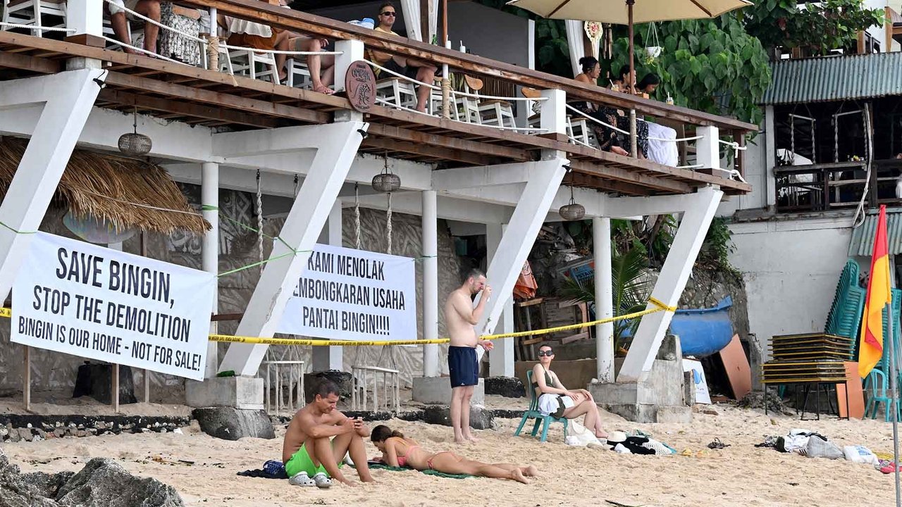 Wisatawan beraktivitas di depan restoran yang dibongkar di Pantai Bingin, Desa Pecatu, Kabupaten Badung, Bali, Rabu (23/07/2025).