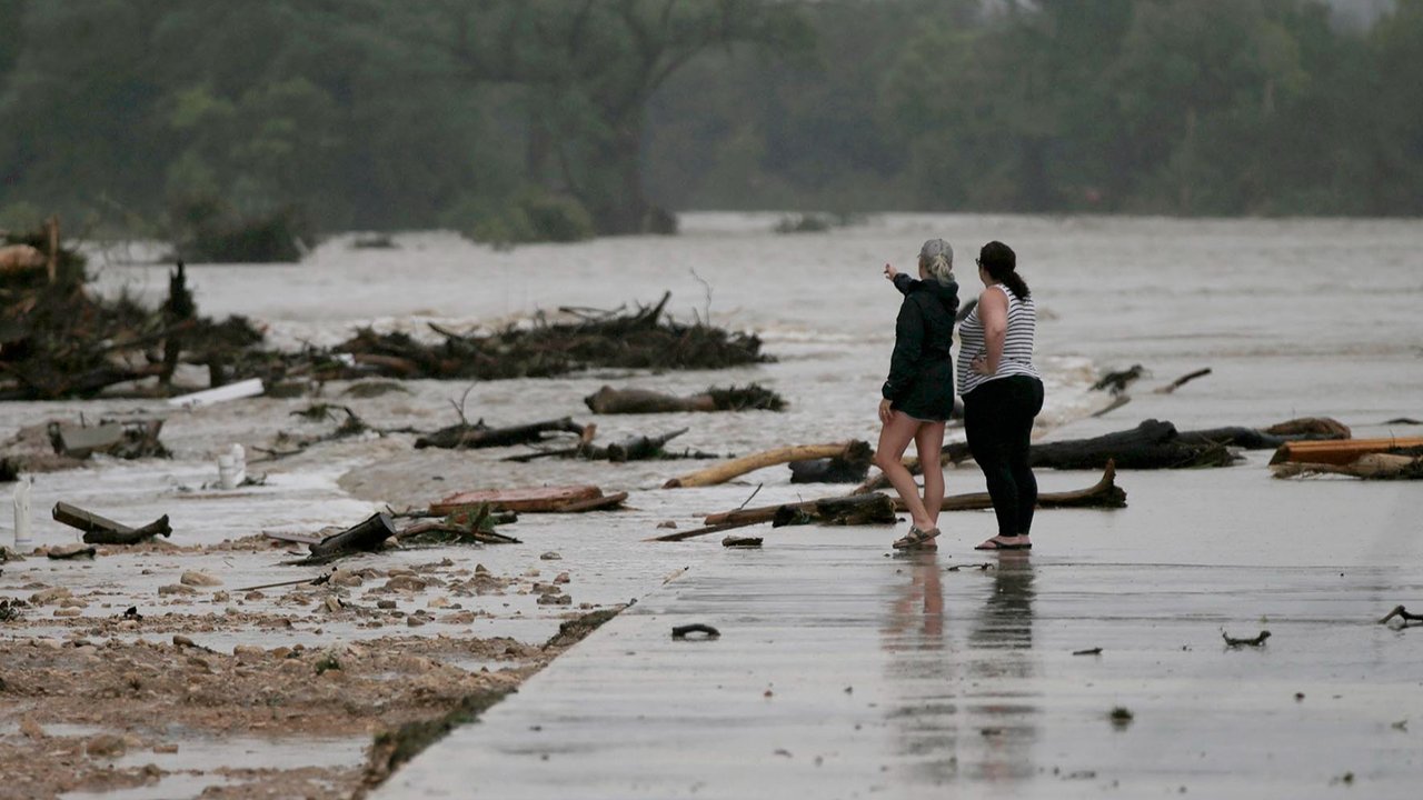 Dua karyawan yang tidak ingin disebutkan namanya, dari HTR RV Park, melihat ke area tempat puluhan trailer tersapu oleh banjir  bandang  di Sungai Guadalupe di Ingram, Texas, Jumat,  (04/07/2025).