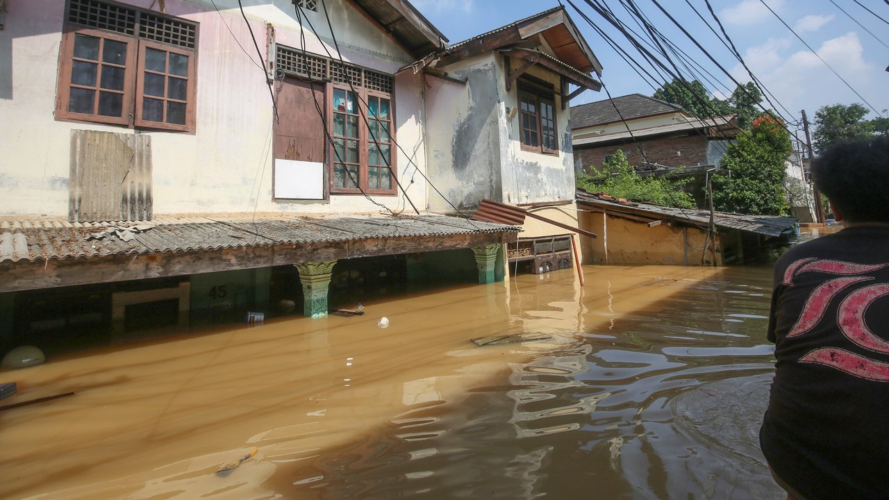 Warga beraktifitas saat banjir merendam pemukiman di Jalan Pirus, Kelurahan Bidara Cina, Jatinegara, Jakarta Timur, Minggu (06/07/2025).