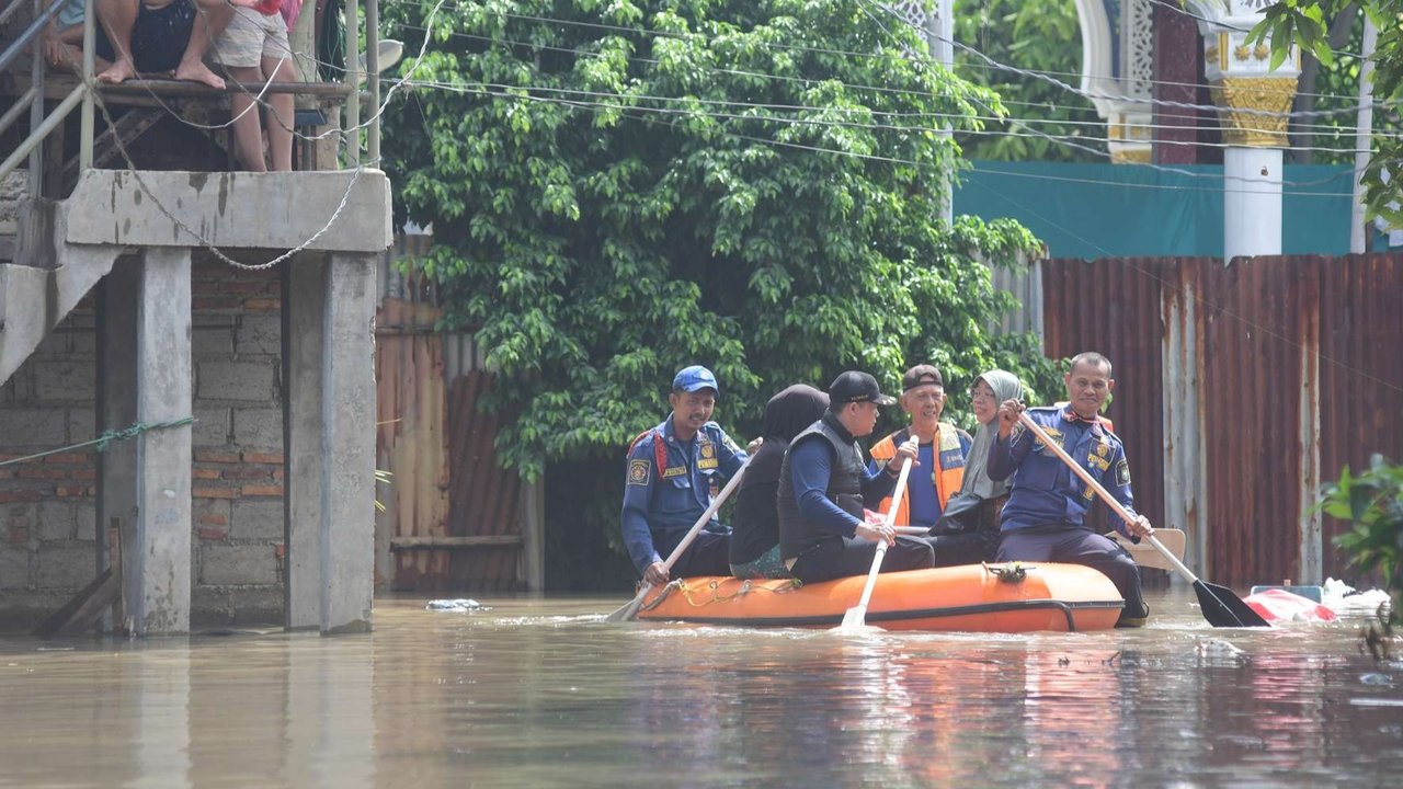 Warga melewati banjir yang merendam Kampung Cantiga, Petir, Cipondoh, Kota Tangerang, pada Selasa (8/7/2025). Kawasan Tangerang saat ini dikepung banjir akibat meluapnya Kali Angke. Sementara, ketinggian banjir yang merendam Kampung Cantiga mencapai 1,8 meter.