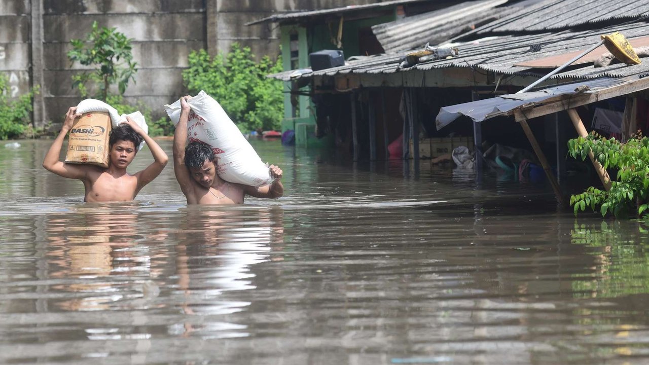 Warga melewati banjir yang merendam Kampung Cantiga, Petir, Cipondoh, Kota Tangerang, pada Selasa (8/7/2025). Kawasan Tangerang saat ini dikepung banjir akibat meluapnya Kali Angke. Sementara, ketinggian banjir yang merendam Kampung Cantiga mencapai 1,8 meter.
