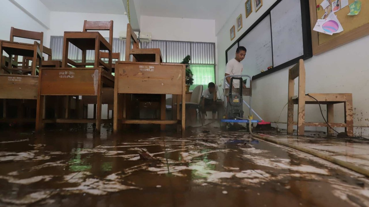 Petugas membersihkan ruang kelas setelah banjir merendam SMAN 60 Jakarta di kawasan Duren Tiga, Jakarta, Selasa (8/7/2025).