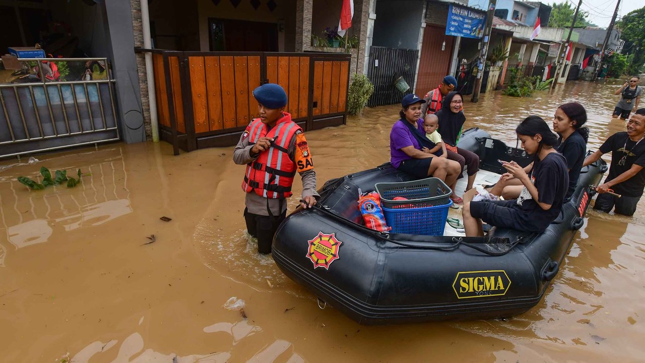 Relawan bersama anggota Brimob Polda Metro Jaya mengevakuasi warga menggunakan perahu karet setelah banjir  merendam kawasan Perumahan Villa Pamulang, Kelurahan Pondok Petir, Kecamatan Bojongsari, Kota Depok, Jawa Barat, Minggu (10/8/2025).