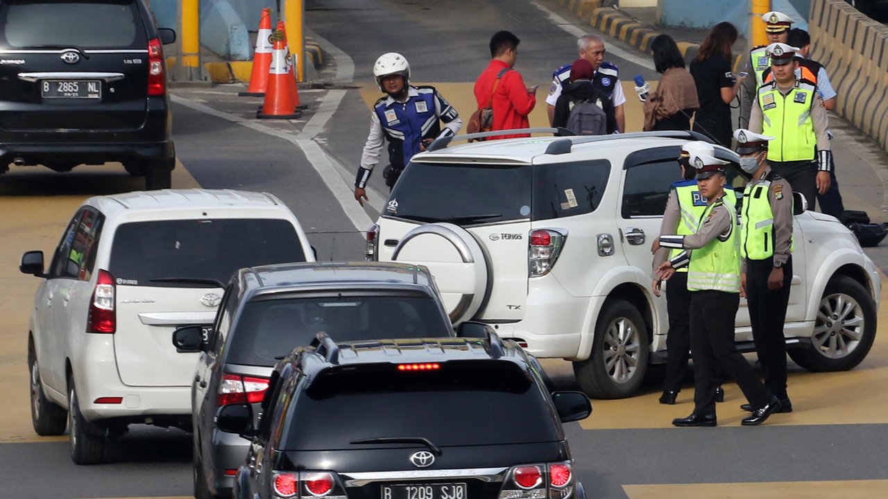 Petugas mengarahkan kendaraan berplat genap berputar balik di Gerbang Tol Bekasi Barat 1, Bekasi, Jawa Barat, Selasa (13/3). Hari kedua penerapan ganjil genap, masih banyak kendaraan berputar balik di gerbang tol tersebut. (Liputan6.com/Arya Manggala)