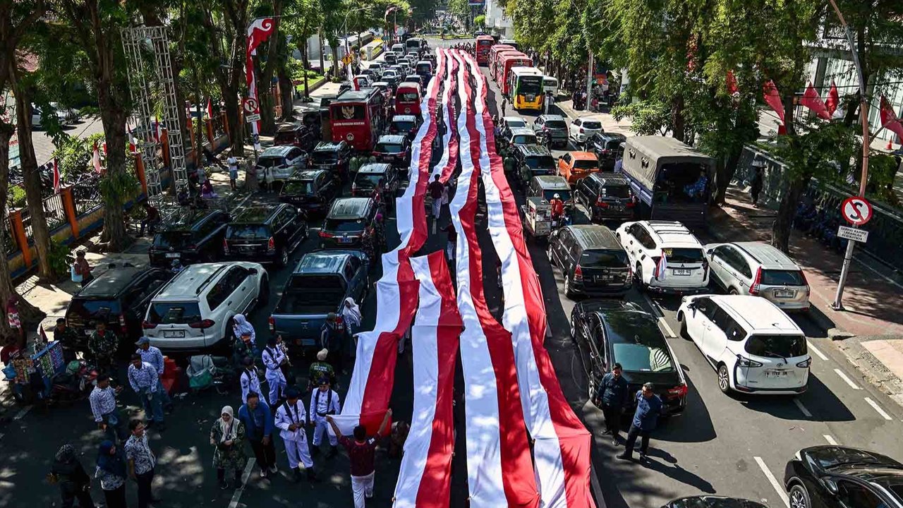 Ribuan pelajar dari berbagai sekolah di Surabaya membentangkan bendera merah putih sepanjang 14. 905 meter di di Jalan Gubernur Suryo Surabaya, Minggu (17/08/2025).