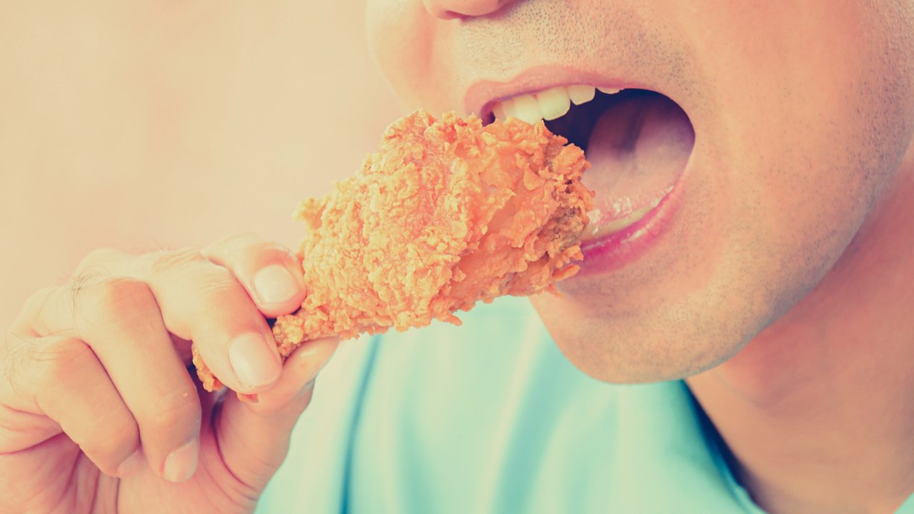 Seorang pria makan ayam goreng.