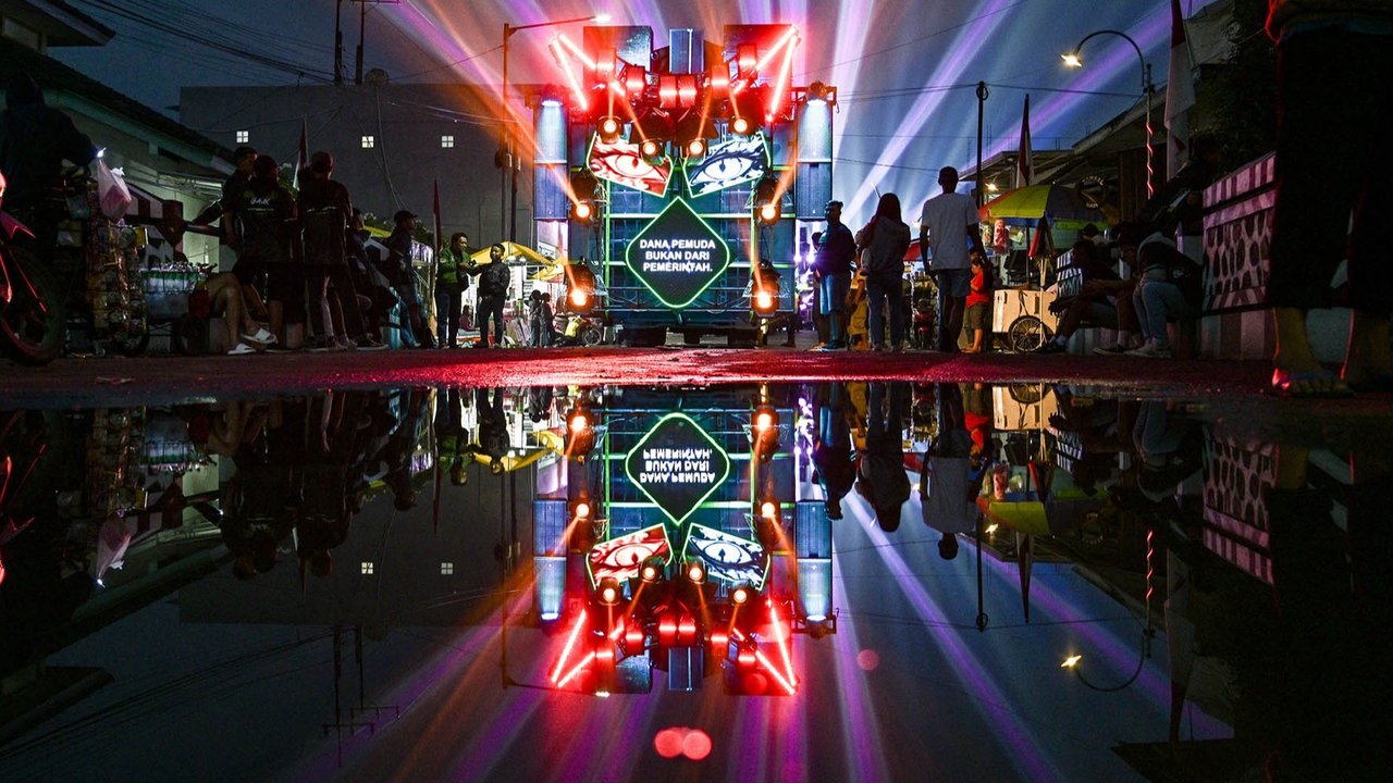 Warga menonton truk yang dipasangi menara subwoofer dan lampu sorot saat kegiatan sound horeg menyambut perayaan Hari Kemerdekaan Indonesia ke-80 di Malang, Jawa Timur (09/08/2025).