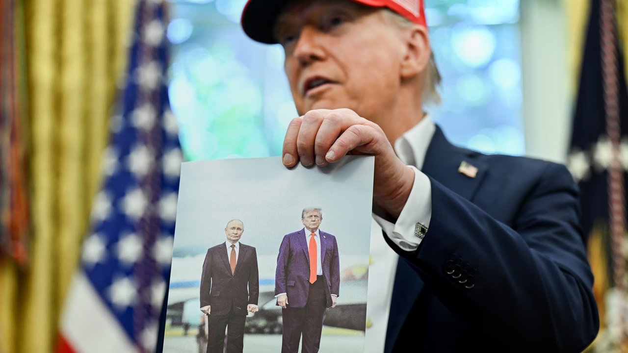 Presiden Donald Trump memperlihatkan sebuah foto dirinya bersama Presiden Rusia Vladimir Putin di Oval Office, Gedung Putih, Washington, Jumat (22/8/2025). (Dok. AP Photo/Jacquelyn Martin)