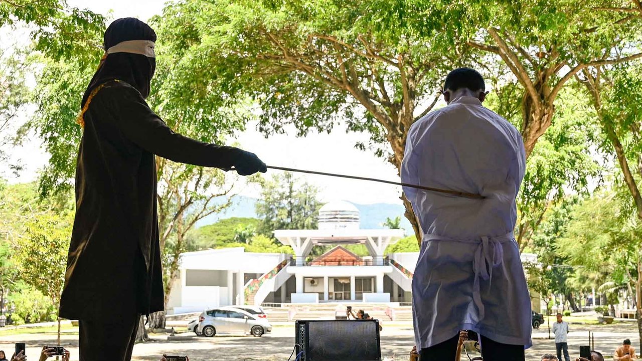 Seorang pria menjalani hukuman cambuk di depan umum oleh anggota polisi syariat di Banda Aceh, Selasa (26/08/2025).