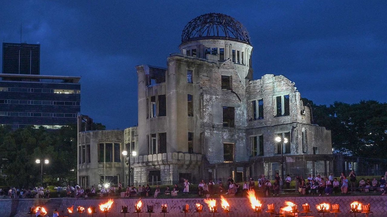 Warga menyaksikan api unggun di sepanjang Sungai Motoyasu di depan Kubah Bom Atom saat peringatan 80 tahun serangan bom atom pertama di kota Hiroshima, Jepang, elasa (05/08/2025).