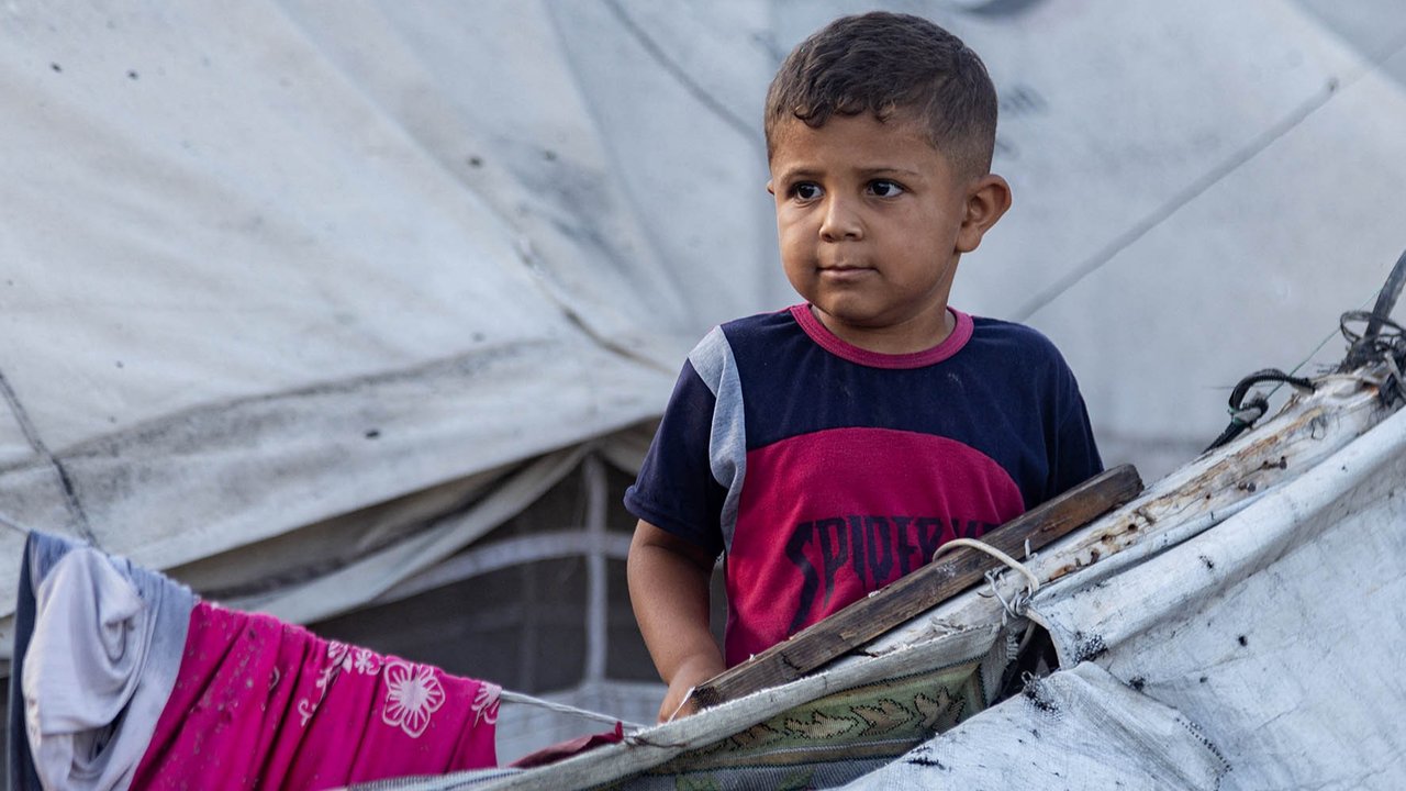 Seorang pria berjalan dengan tongkat saat memeriksa lokasi kejadian pasca-pengeboman Israel semalam di sebuah kamp penampungan pengungsi di daerah Mawasi, Khan Yunis, Jalur Gaza selatan, Selasa (05/08/2025). AFP