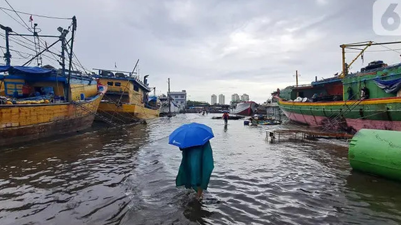 Nelayan melintasi banjir rob saat cuaca ekstrem di Pelabuhan Muara Baru, Penjaringan, Jakarta Utara, Rabu (28/12/2022). Banjir ROB, hujan deras dan cuaca buruk melanda kawasan Pelabuhan Muar