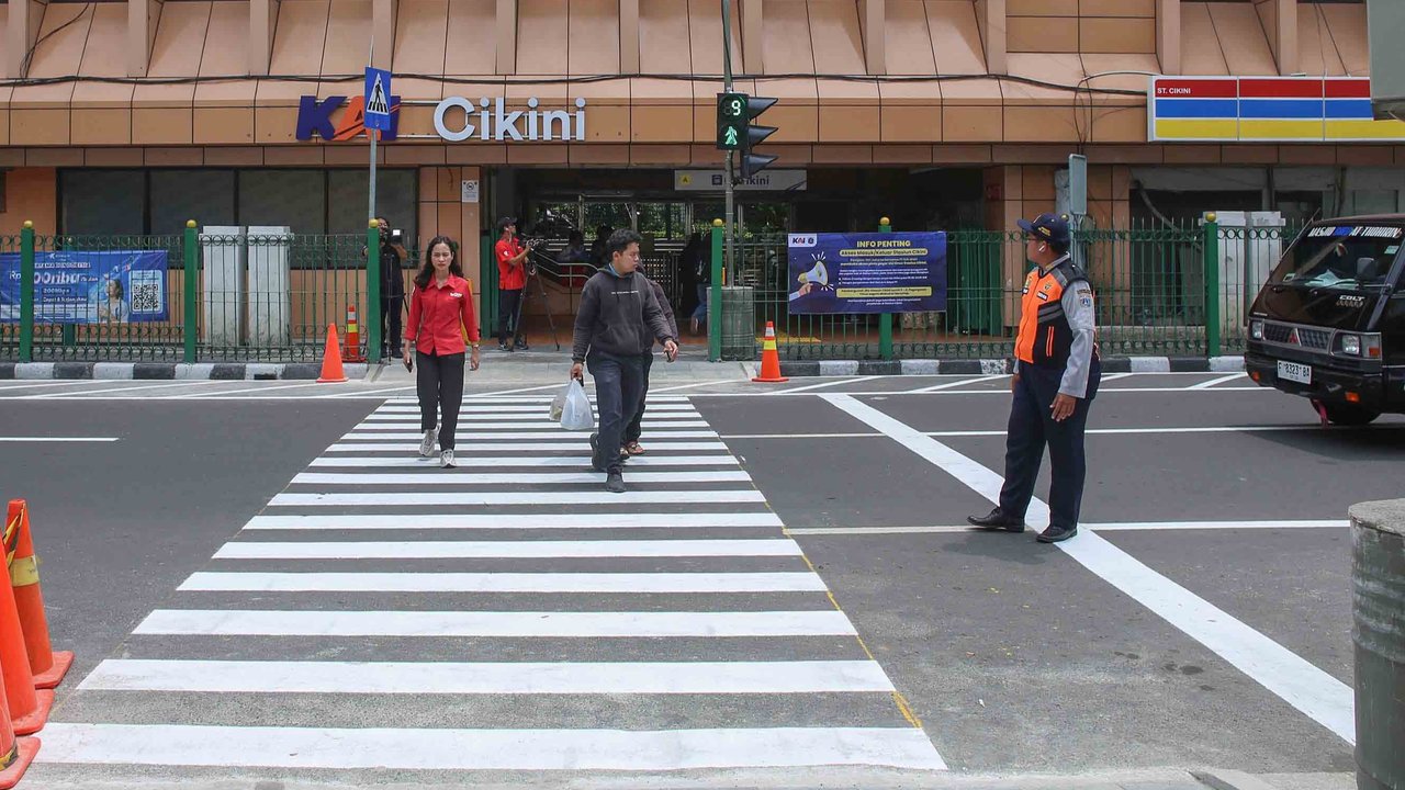 Pejalan kaki melintasi penyeberangan pejalan kaki yang dikontrol lampu lalu lintas atau dikenal sebagai persimpangan pelikan (pelican crossing) di  sisi timur Stasiun Cikini, Jakarta, Senin (15/09/2025).