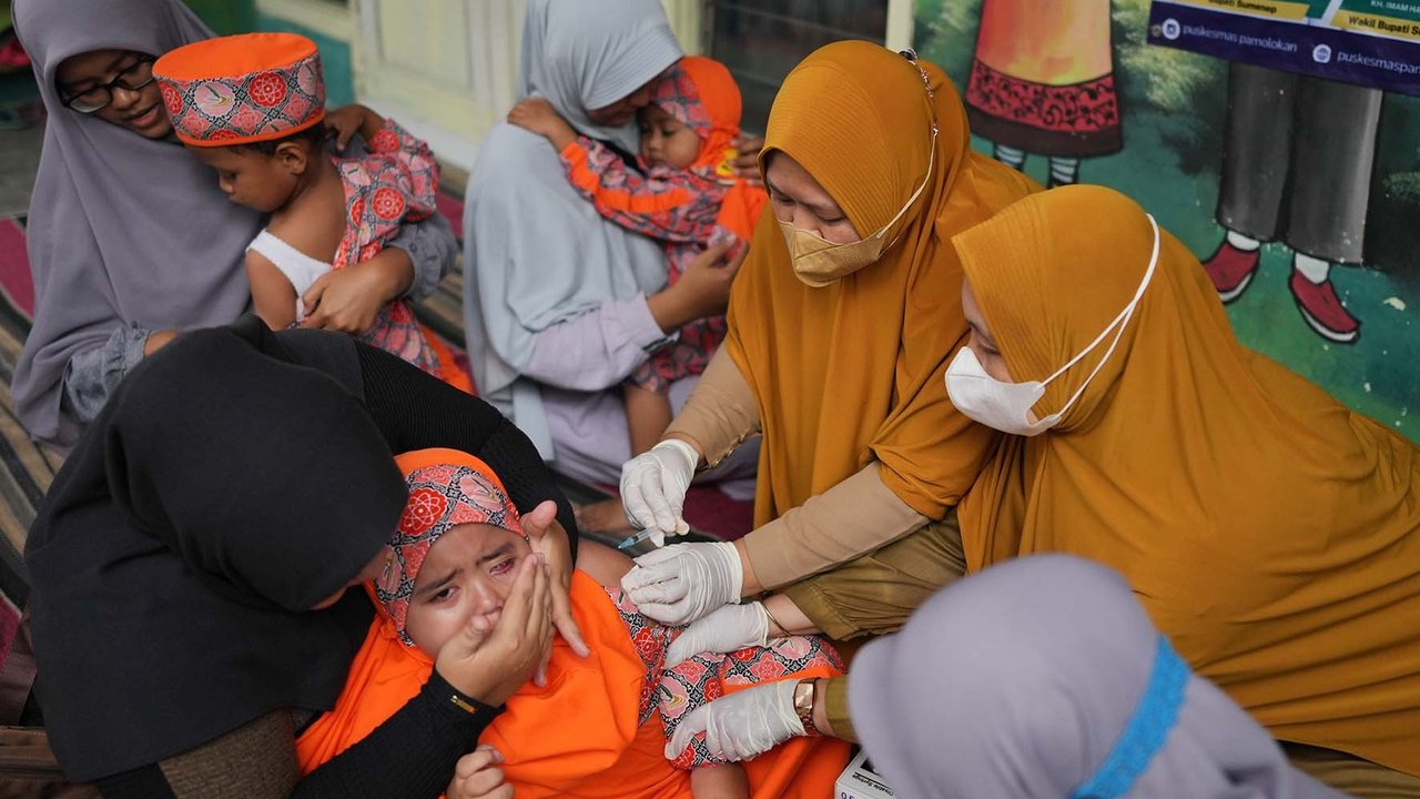 Petugas kesehatan memberikan suntikan campak kepada seorang anak saat  kampanye vaksinasi pasca-wabah di sebuah TK di Sumenep, Madura, Jawa Timur (08/09/ 2025).