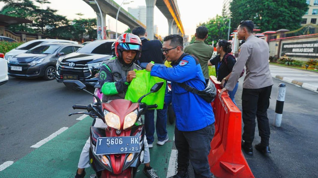 Buruh bersama  anggota Polri membagikan paket sembako di perempatan depan Mabes Polri, Jalan Trunojoyo, Jakarta, Kamis sore (05/09/2025).