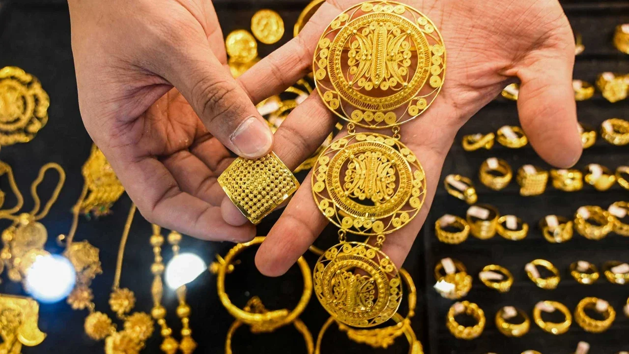 Seorang karyawan memegang beberapa perhiasan emas di sebuah toko perhiasan di Banda Aceh, Rabu (14/01/2026).