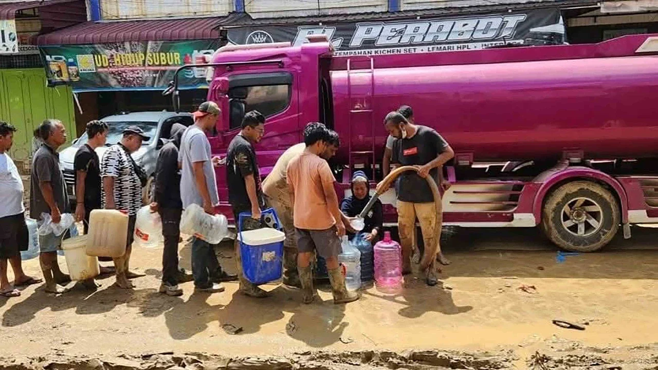 Warga beristirahat saat mencari sisa-sisa harta benda mereka dari rumah mereka yang terkubur tumpukan batang kayu di desa Lintang Bawah, Aceh Tamiang, Aceh, Kamis (11/12/2025).