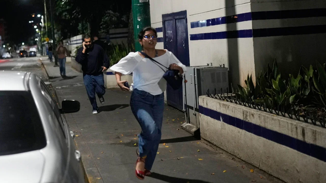 Para pejalan kaki berlari setelah terdengar ledakan dan pesawat terbang rendah di Caracas, Venezuela, Sabtu, (-3/01/2026).