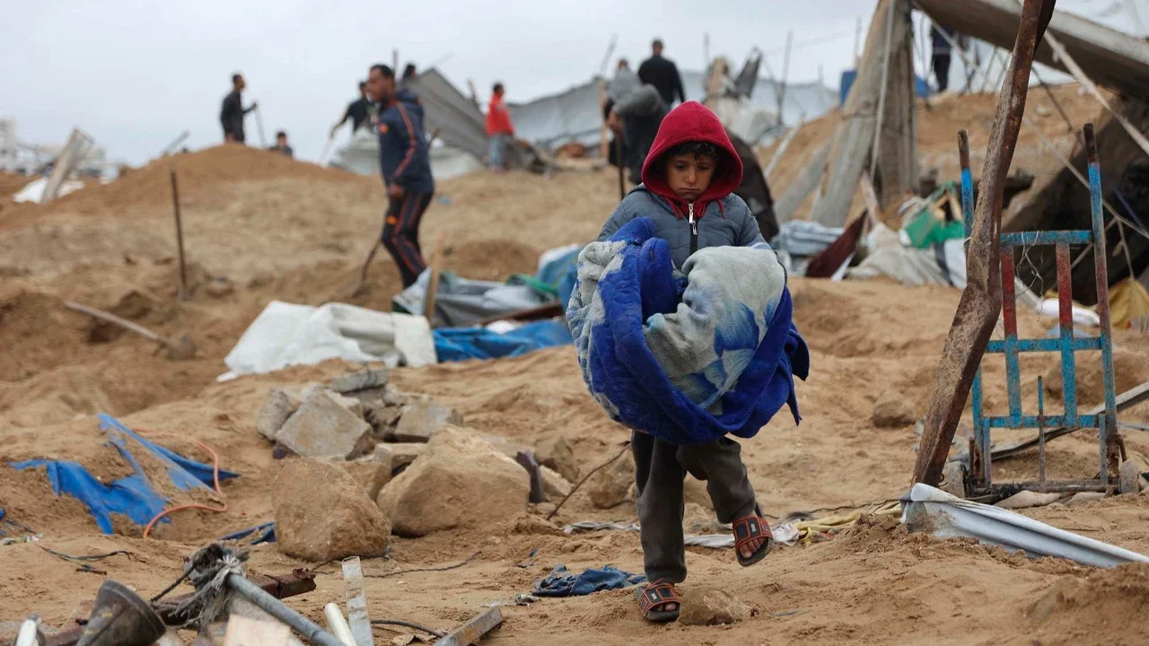 Seorang anak Palestina menyelamatkan beberapa barang miliknya, sehari setelah militer Israel menembaki kamp tenda yang menampung keluarga pengungsi, di kamp pengungsi Al-Shati, di Kota Gaza, Palestina,  Jumat (09/01/2026).