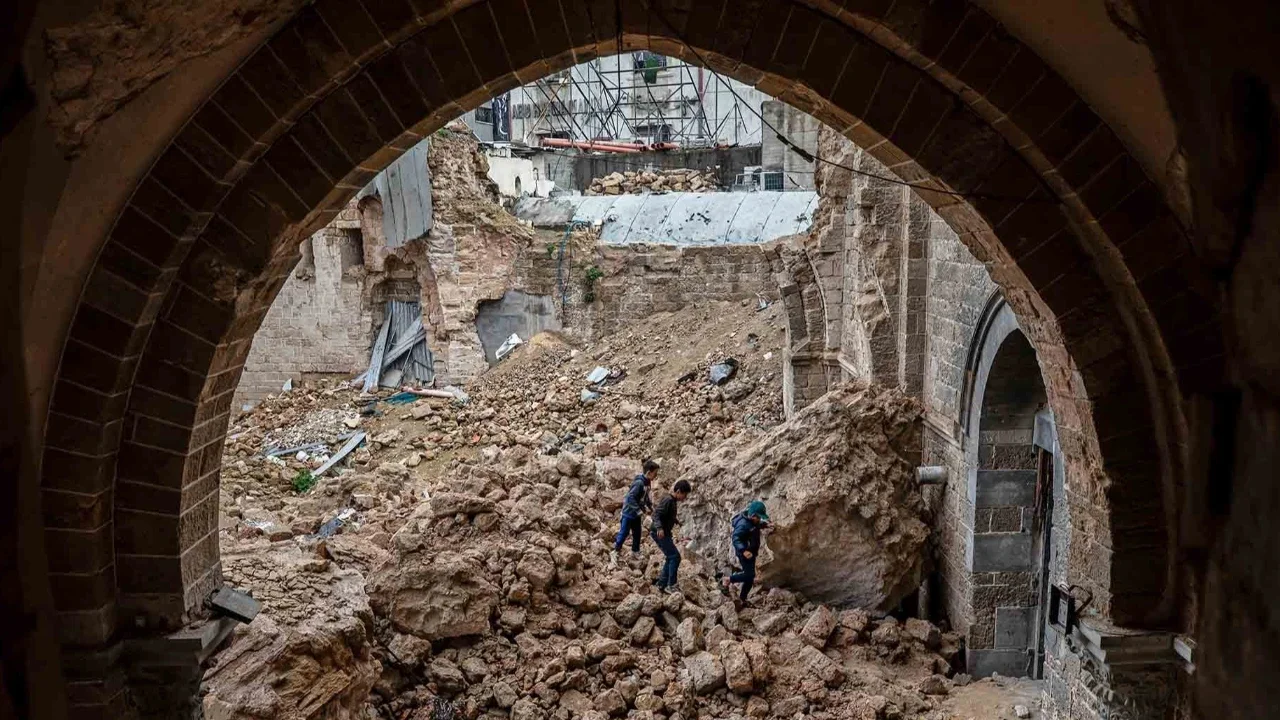 Anak-anak Palestina berjalan melewati reruntuhan Masjid Agung Omari yang rusak akibat serangan Israel di Kota Gaza,  Rabu (12/02/2026).