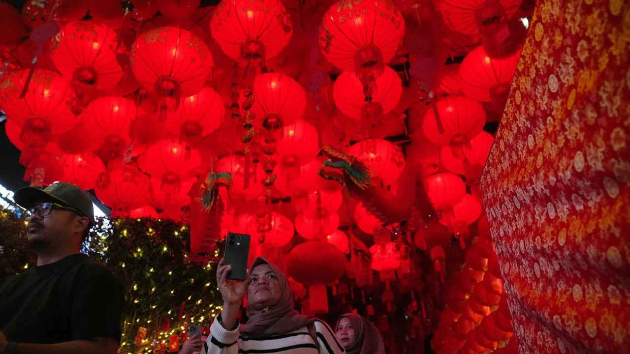 Warga berfoto di instalasi lampu saat perayaan Festival Imlek Jakarta di Bundaran HI, Jakarta, Jumat (13/2/2026) malam.