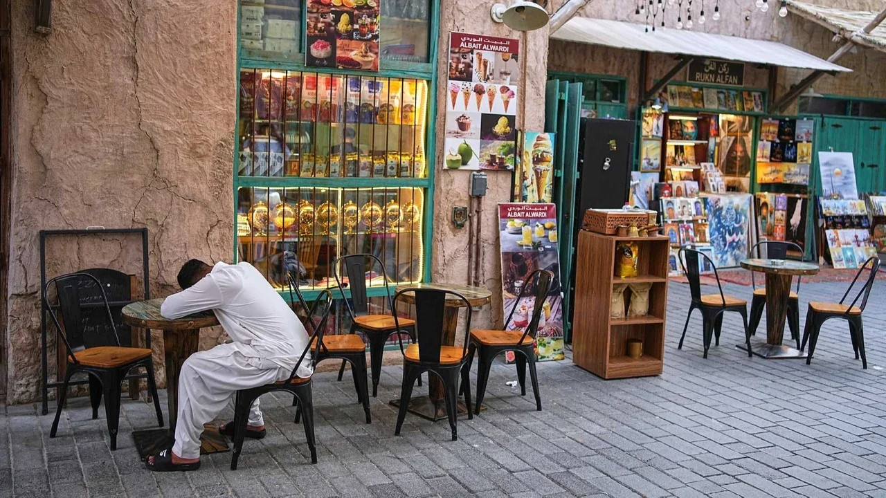 Seorang pria tidur siang di atas meja kafe di pasar Al Seef yang kosong di Dubai, Uni Emirat Arab, Jumat, (13/03/2026).
