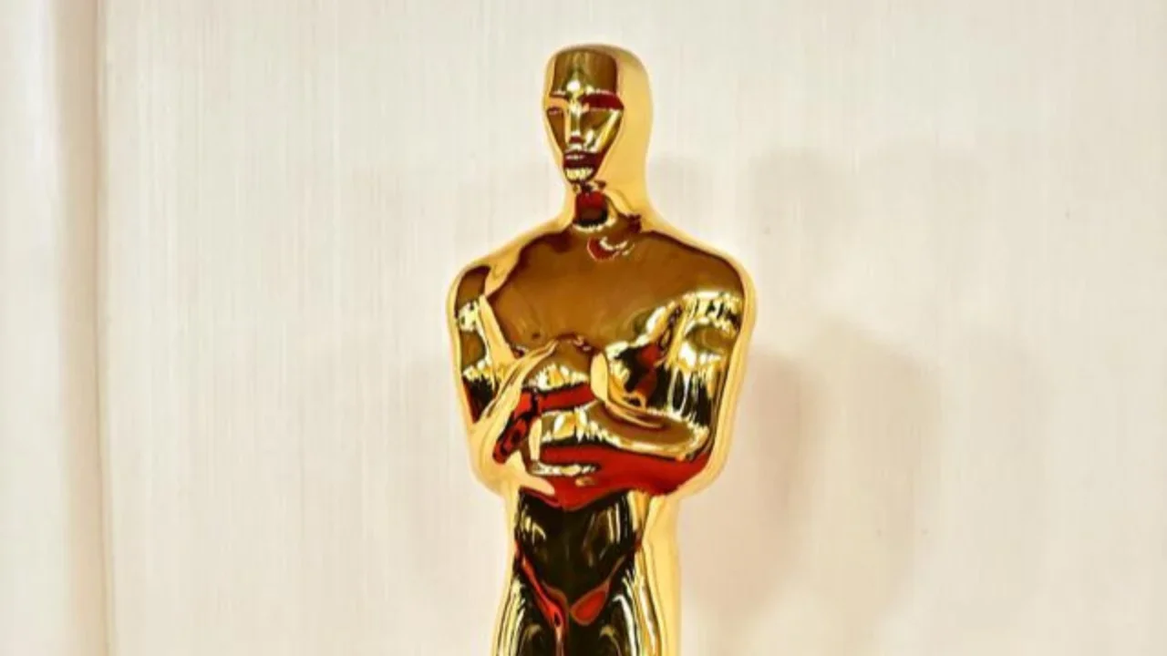 Seorang pria melewati replika patung Oscar pada hari Sabtu, 14 Maret 2026, di jalan dekat Dolby Theatre di Los Angeles, tempat persiapan terus berlangsung untuk upacara Academy Awards ke-98 p