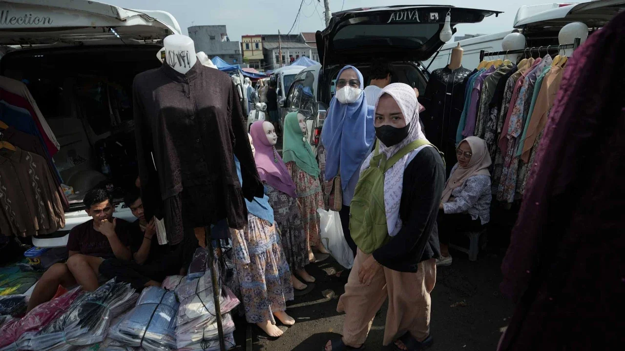 Warga berjalan melewati kendaraan pedagang yang menjual pakaian di Pasar Tasik, Cideng, Jakarta, Senin, (09/03/2026).